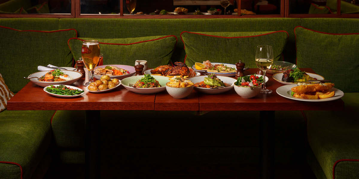a wooden table with lots of dishes on it and a beer glass and a wine glass