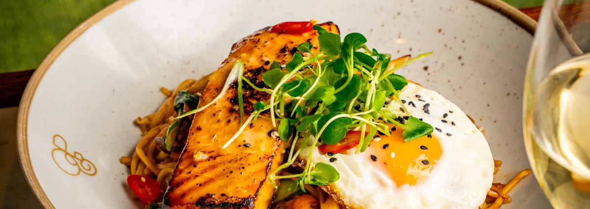 Noodles with vegetables and salmon with a glass of wine